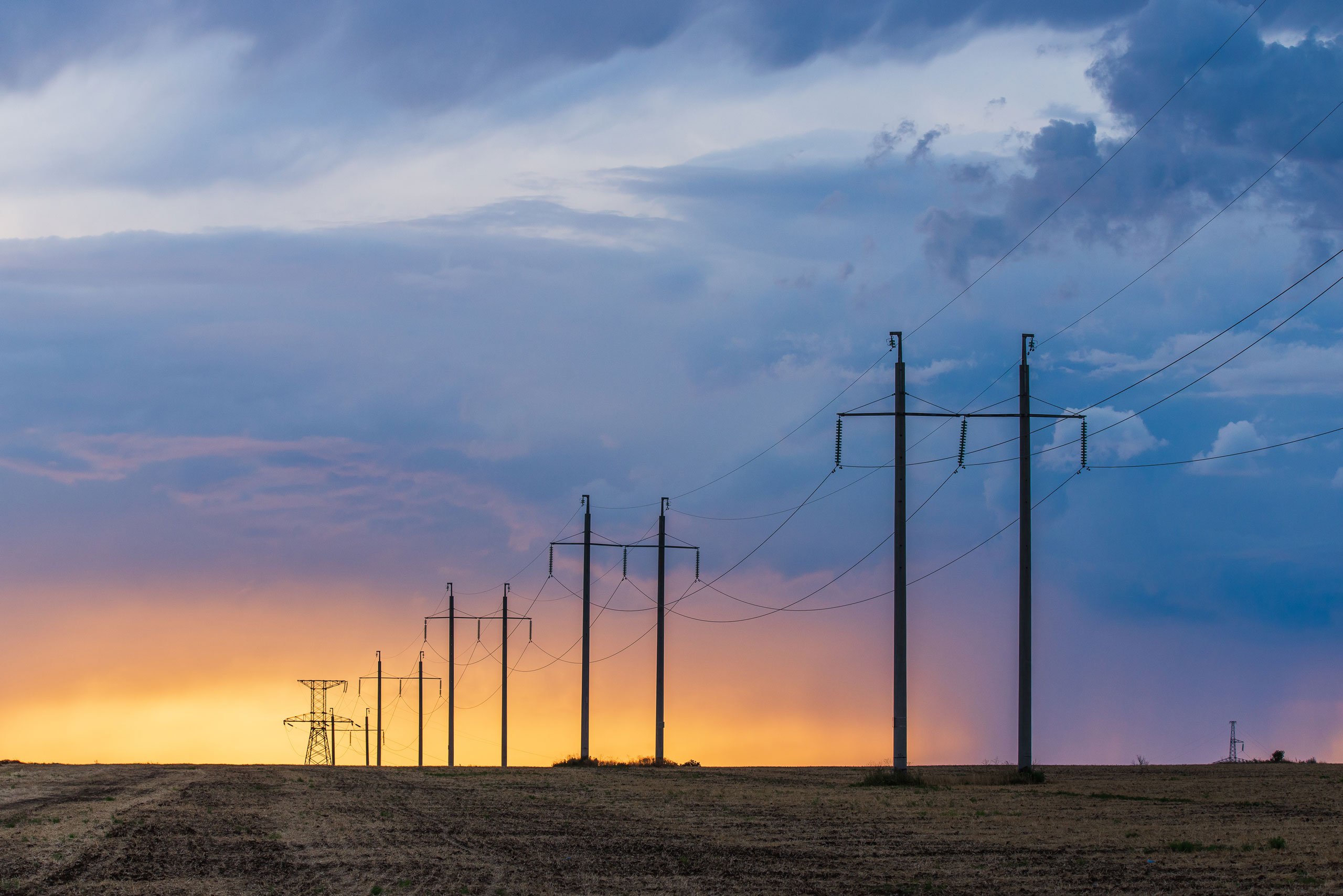 Transmission towers against a sunset in the countryside