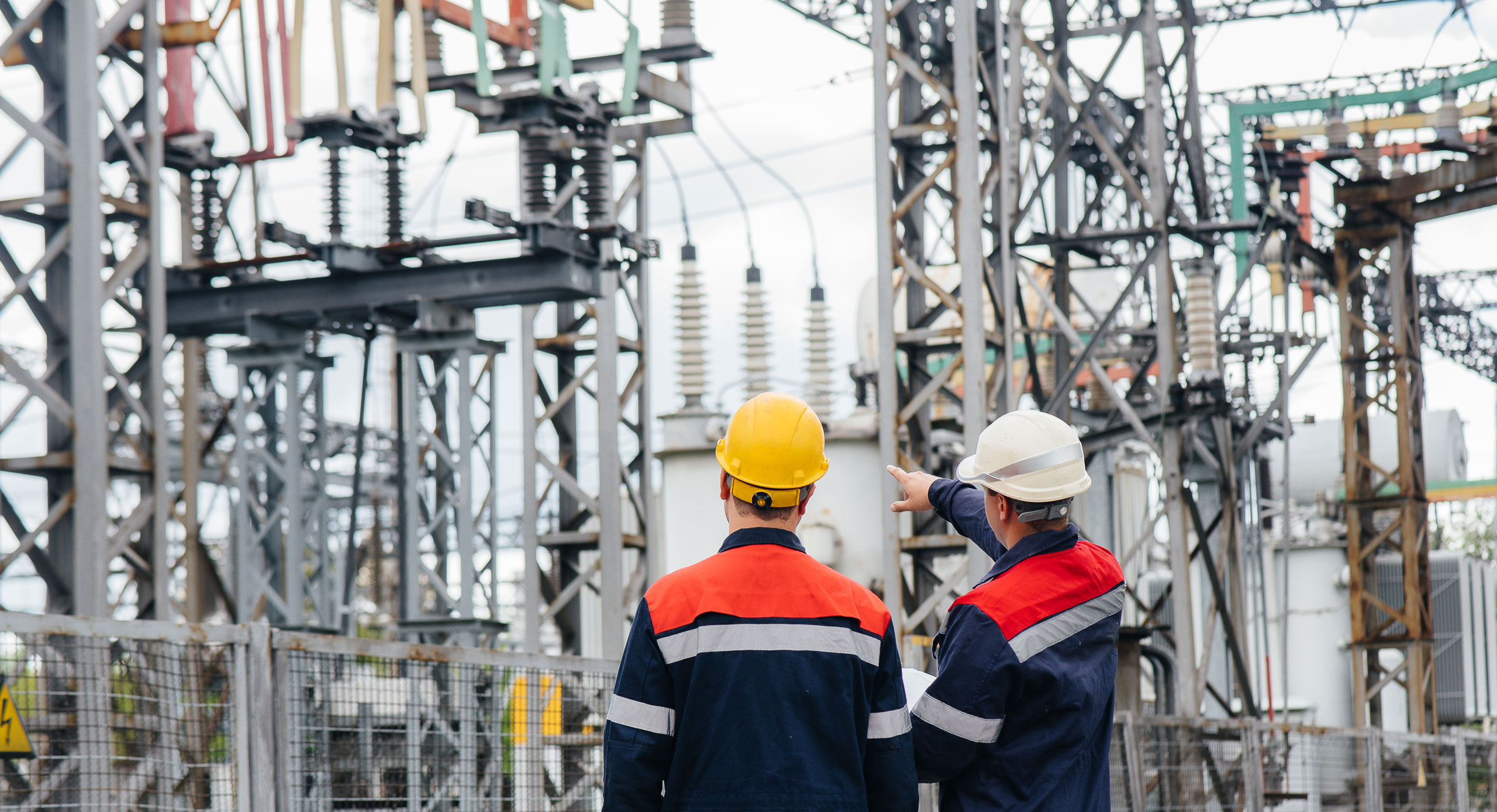 Two specialist electrical substation engineers inspect modern high-voltage equipment.