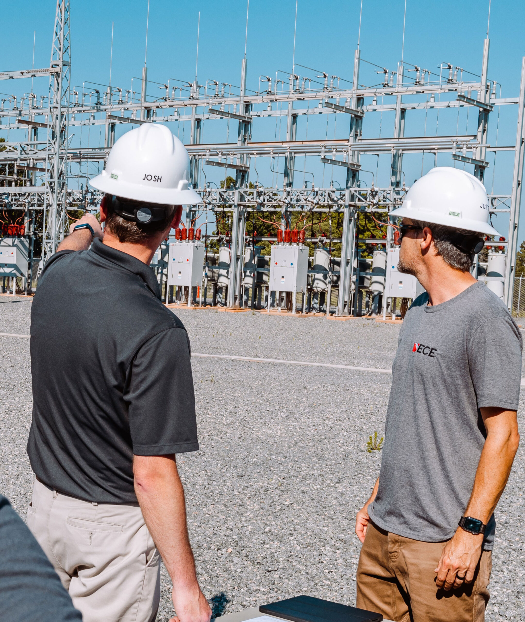 ECE team leader pointing out a feature at a substation to another staff member.